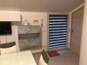 een keuken met een tafel en een raam met jaloezieën bij Mansarda Mentana due in Vittoria