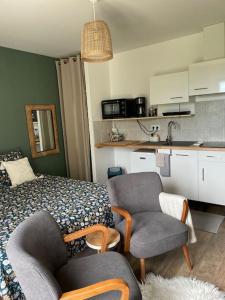 a bedroom with a bed and chairs and a kitchen at Le nid du vallon in Pomport