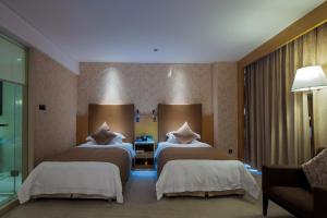 una camera d'albergo con due letti e un divano di Wudang International Hotel a Shiyan Altre 16 foto