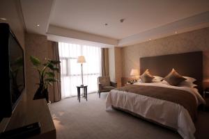 ein Hotelzimmer mit einem großen Bett und einem Fernseher in der Unterkunft Wudang International Hotel in Shiyan