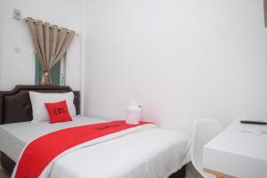 a white bedroom with a bed with red pillows at RedDoorz Plus At Lovina Inn Tonrangeng River Side in Parepare