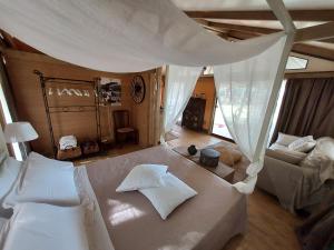 a bedroom with a large white bed and a couch at Wine Glamping Le Sedici in Massa Marittima