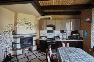 a kitchen with a fireplace and a table with chairs at Садиба у Кіри in Slavske