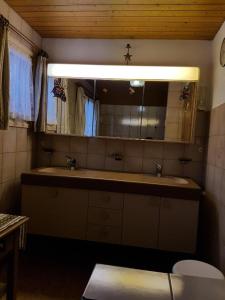 uma casa de banho com um lavatório, um espelho e um WC. em Zimmer für Backpaking - Das gemütliche Haus des Grossvaters - Bergheimat - Ganz einfach - ganz unkompliziert - ganz relaxd em Linthal