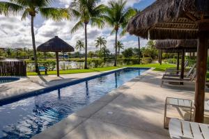 a swimming pool with palm trees and a resort at Refúgio na Praia do Forte in Praia do Forte