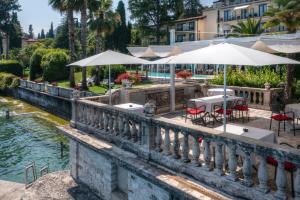 a bridge over a river with tables and umbrellas at Hotel Villa Capri in Gardone Riviera