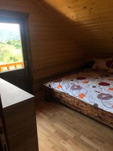 a bedroom with a bed in a cabin with a window at Casa din Deal in Moldoveneşti