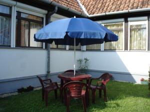 a table and chairs under a blue umbrella at Liza Apartman in Gyula