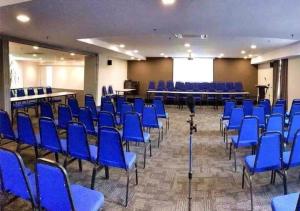 a conference room with blue chairs and a screen at Hotel Pi Ipoh in Ipoh