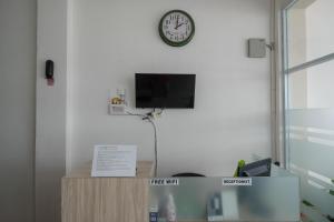 a room with a tv and a clock on a wall at RedDoorz Plus At Lovina Inn Tonrangeng River Side in Parepare