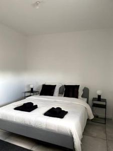 ein Schlafzimmer mit einem großen weißen Bett mit schwarzen Kissen in der Unterkunft Maison 90m2 Lormont 3 chambres et jardin in Lormont