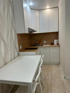 a kitchen with white cabinets and a table and chairs at Аэропорт 5 минут in Prigorodnyy