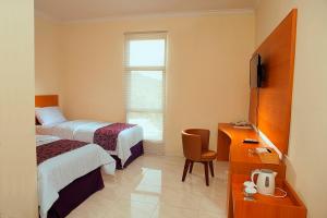 une chambre d'hôtel avec deux lits et une télévision dans l'établissement kahai beach hotel, à Waimuli