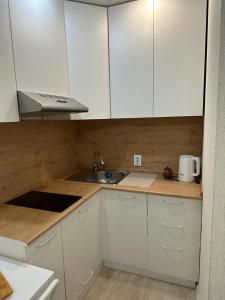 uma cozinha com armários brancos e um lavatório em Аэропорт 5 минут em Prigorodnyy