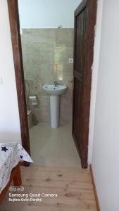 a bathroom with a sink and a toilet and a door at Guest House Qafe Dardha - Tomorr National Park in Dardhë
