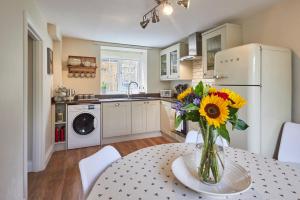 a kitchen with a table with a vase of flowers at Host & Stay - North Cottage in Newbrough