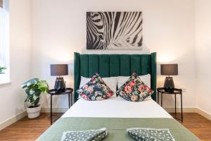 una camera con un letto con un testata verde e due lampade di Fashionable Brick Lane a Londra