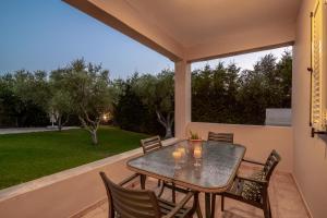patio con mesa y sillas en el balcón en Planos Villa en Tsilivi