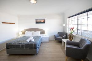 a bedroom with a bed and a couch and two chairs at Clearwater Motel Apartments in Esperance