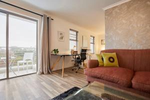 een woonkamer met een bank, een bureau en een raam bij Rondebosch Central in Kaapstad