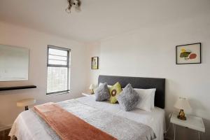 a white bedroom with a large bed with pillows at Rondebosch Central in Cape Town