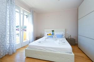 ein weißes Schlafzimmer mit einem weißen Bett und einem Fenster in der Unterkunft Villa Iris in Manerba del Garda