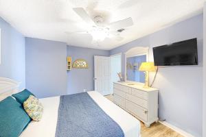 een blauwe slaapkamer met een bed en een flatscreen-tv bij Sunset Harbour Villas 1-112 in Navarre