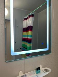 einen Badezimmerspiegel mit einem Regenbogen-Duschvorhang und einem Waschbecken in der Unterkunft Аэропорт 5 минут in Prigorodnyy