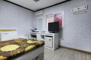 a bedroom with a bed and a desk with a television at Dream of City Motel in Daegu