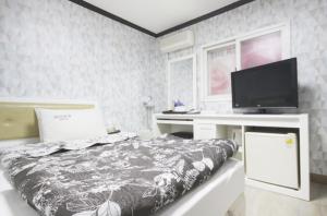 een slaapkamer met een bed en een bureau met een televisie bij Dream of City Motel in Daegu