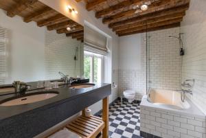 bagno con 2 lavandini, vasca e servizi igienici di Fletcher Hotel Château De Raay a Baarlo