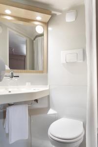 La salle de bains blanche est pourvue de toilettes et d'un lavabo. dans l'établissement Première Classe Châlons-en-Champagne, à Saint-Martin-sur-le-Pré