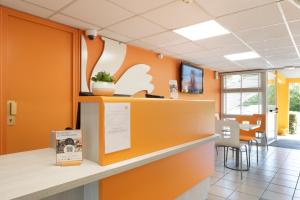 un bureau avec des murs orange et un comptoir de réception dans l'établissement Première Classe Châlons-en-Champagne, à Saint-Martin-sur-le-Pré