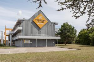 a building with a large yellow sign on it at Première Classe Châlons-en-Champagne in Châlons-en-Champagne