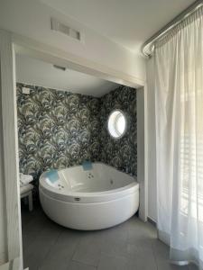 Hotel Tasso Suites & Spa في سورينتو: حوض استحمام في حمام مع جدار