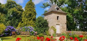 a stone tower in a garden with flowers at chateau du Bois-Riou in Quévert