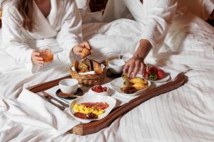 - une femme au lit avec un plateau de produits pour le petit-déjeuner dans l'établissement Chateau Du Boisniard, à Chambretaud