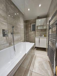 cosy 1-Bed Apartment in London Alexandra Palace في لندن: حمام كبير مع حوض ومغسلة