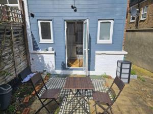 a blue house with two chairs in front of it at cosy 1-Bed Apartment in London Alexandra Palace in London