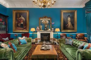 una sala de estar con paredes azules y sofás verdes en The Gore London - Starhotels Collezione en Londres