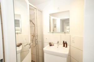 a white bathroom with a sink and a shower at Kapitän's Koje Wangerooge in Wangerooge