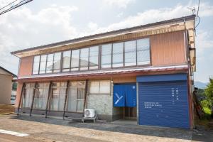 an old building with a blue door in front of it at 町宿ORANCHI 