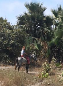 a woman riding a horse on a dirt road at Marysa Lodge in Kotu