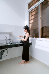 een vrouw in een zwarte jurk in een keuken bij Minh Minh Nam 2 Hotel in Can Tho