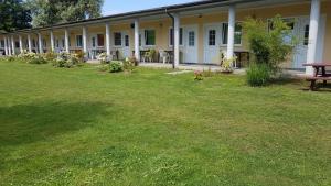 a building with a grass yard with a bench in front of it at POMERANIA Pokoje U Oliwii in Rewal