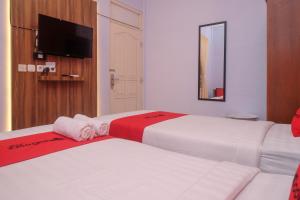 2 camas en una habitación de hotel con TV en la pared en RedDoorz At Pondok Eyang Obi Sleman en Yogyakarta