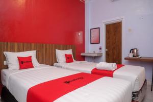2 camas en una habitación con rojo y blanco en RedDoorz At Pondok Eyang Obi Sleman en Yogyakarta