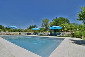 einen Pool mit blauen Sonnenschirmen und Stühlen in der Unterkunft Gîte Le Bon Sens - Domaine la Rose des vents in Castelnau-sur-lʼAuvignon