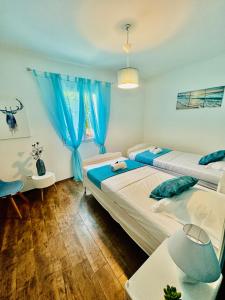 Dos camas en una habitación con cortinas azules. en "Villa Bernardini" vacances paisible à 2km de la mer, en Ventiseri