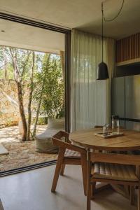 a dining room with a table and a sliding glass door at Teva Tulum, Aldea Zamá in Tulum